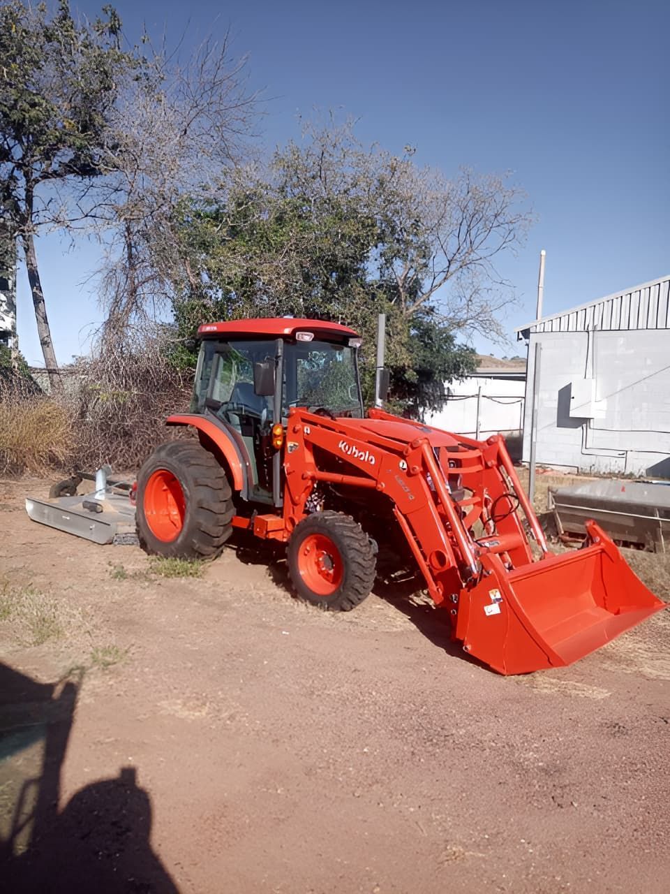 A Red Tractor With A Large Bucket Is Parked In A Dirt Lot — Mount Isa Skips In Mount Isa, QLD