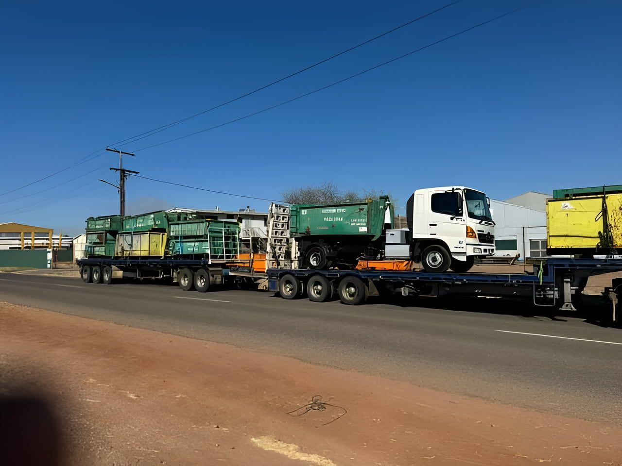 A Row Of Garbage Trucks Are Parked On The Side Of The Road — Mount Isa Skips In Mount Isa, QLD
