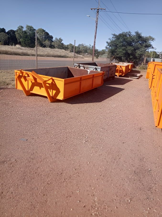 A Row Of Orange Dumpsters On A Dirt Road — Mount Isa Skips In Mount Isa, QLD