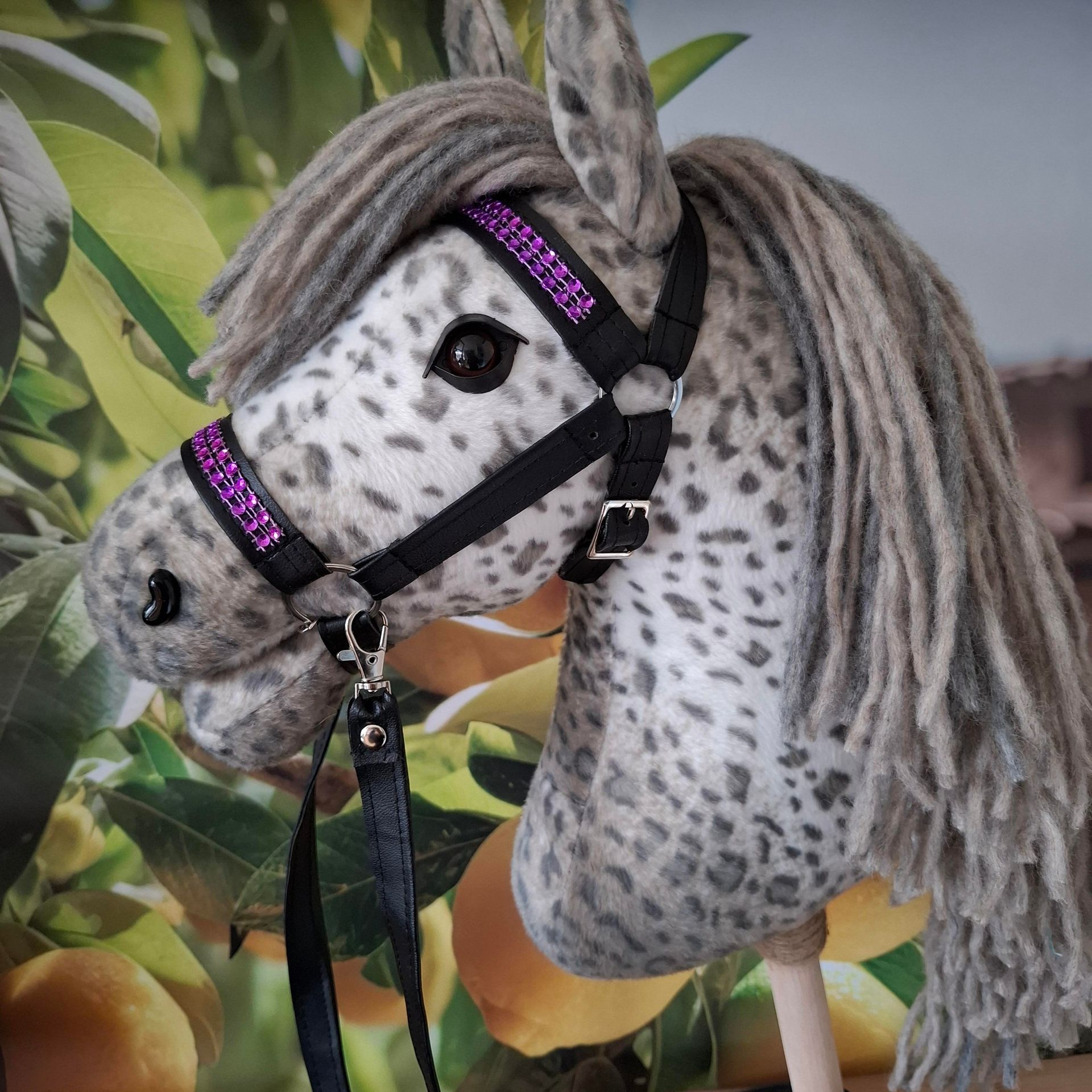 Een collage van een grijs-wit gevlekt stokpaard met een zwart-paars hoofdstel.