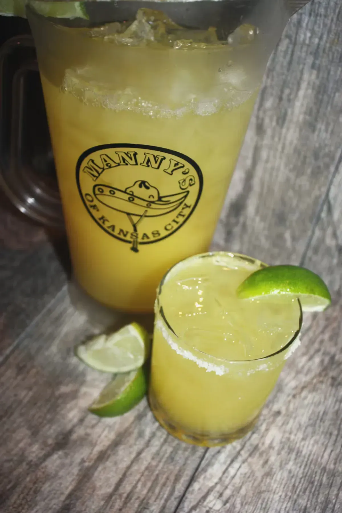 Pitcher and glass of margarita; yellow drink, lime garnish, salt rim. 