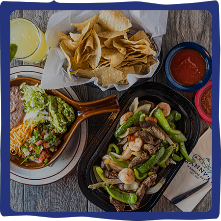 Mexican food spread: chips, salsa, fajitas, guacamole, beans, drink.