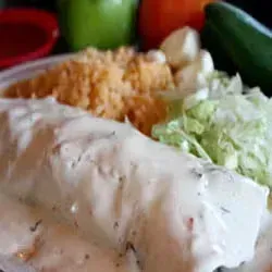 Burrito with creamy sauce, rice, lettuce, and a side of salsa.