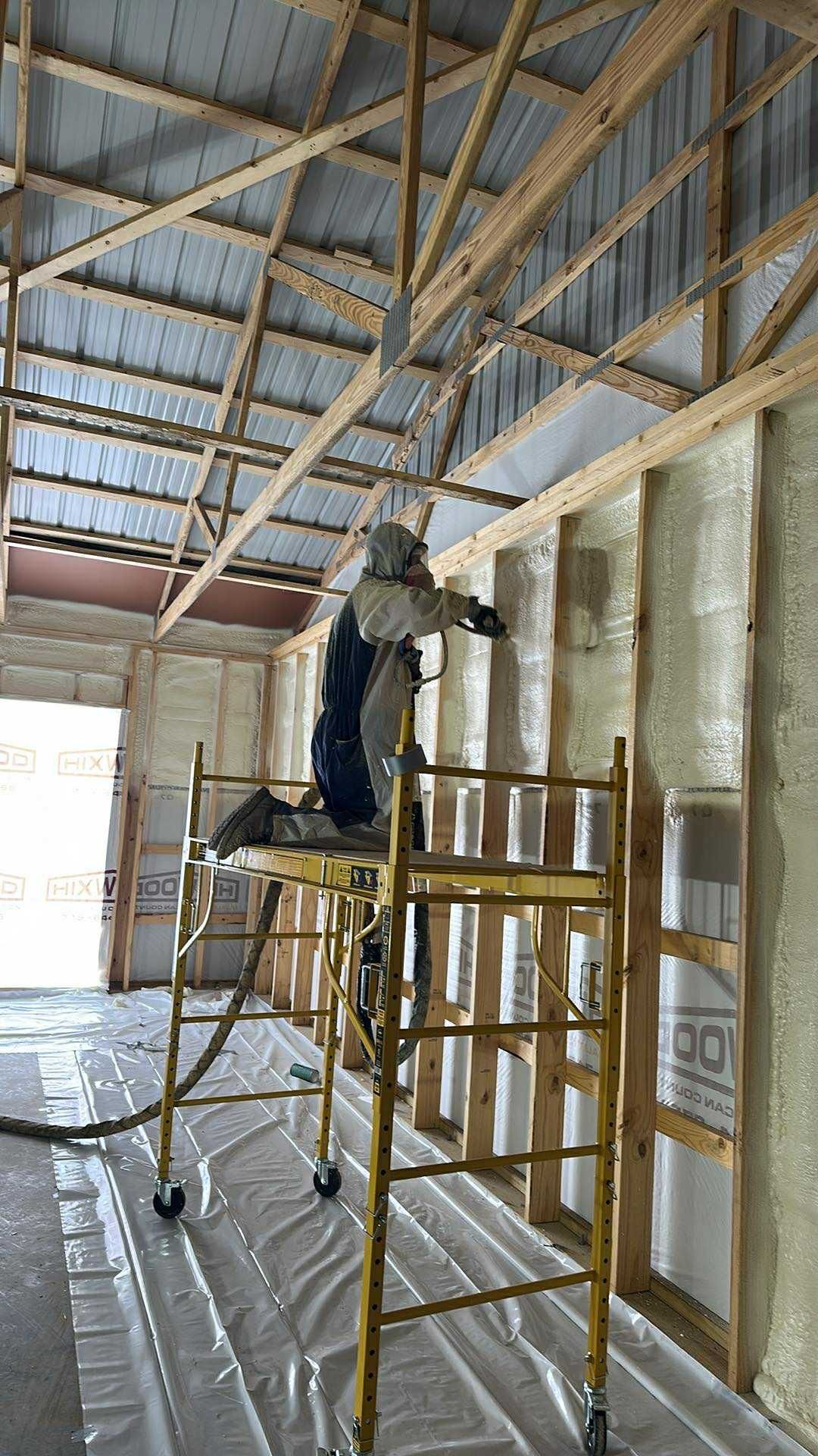 Worker applying spray foam insulation to the wall