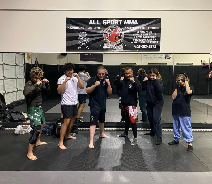 A group of people standing in front of a sign that says all sport mma