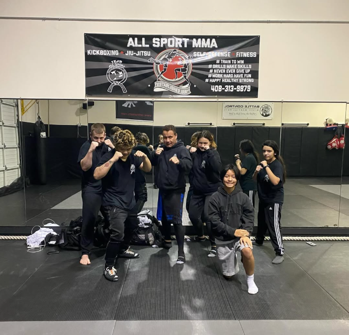 A group of people standing in front of a sign that says all sport mma