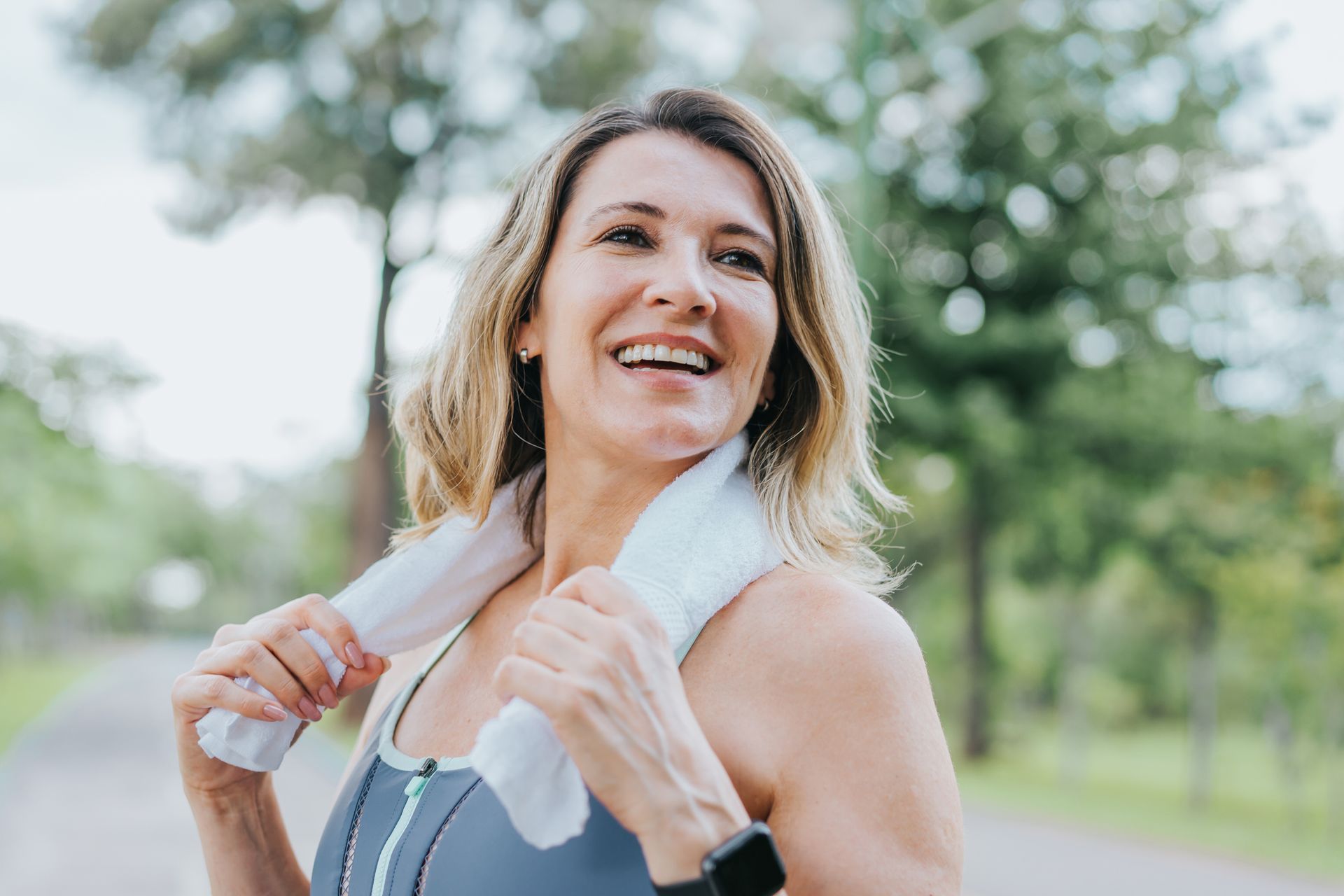 A woman is smiling while holding a towel around her neck.