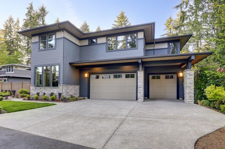 A large house with two garage doors and a concrete driveway.