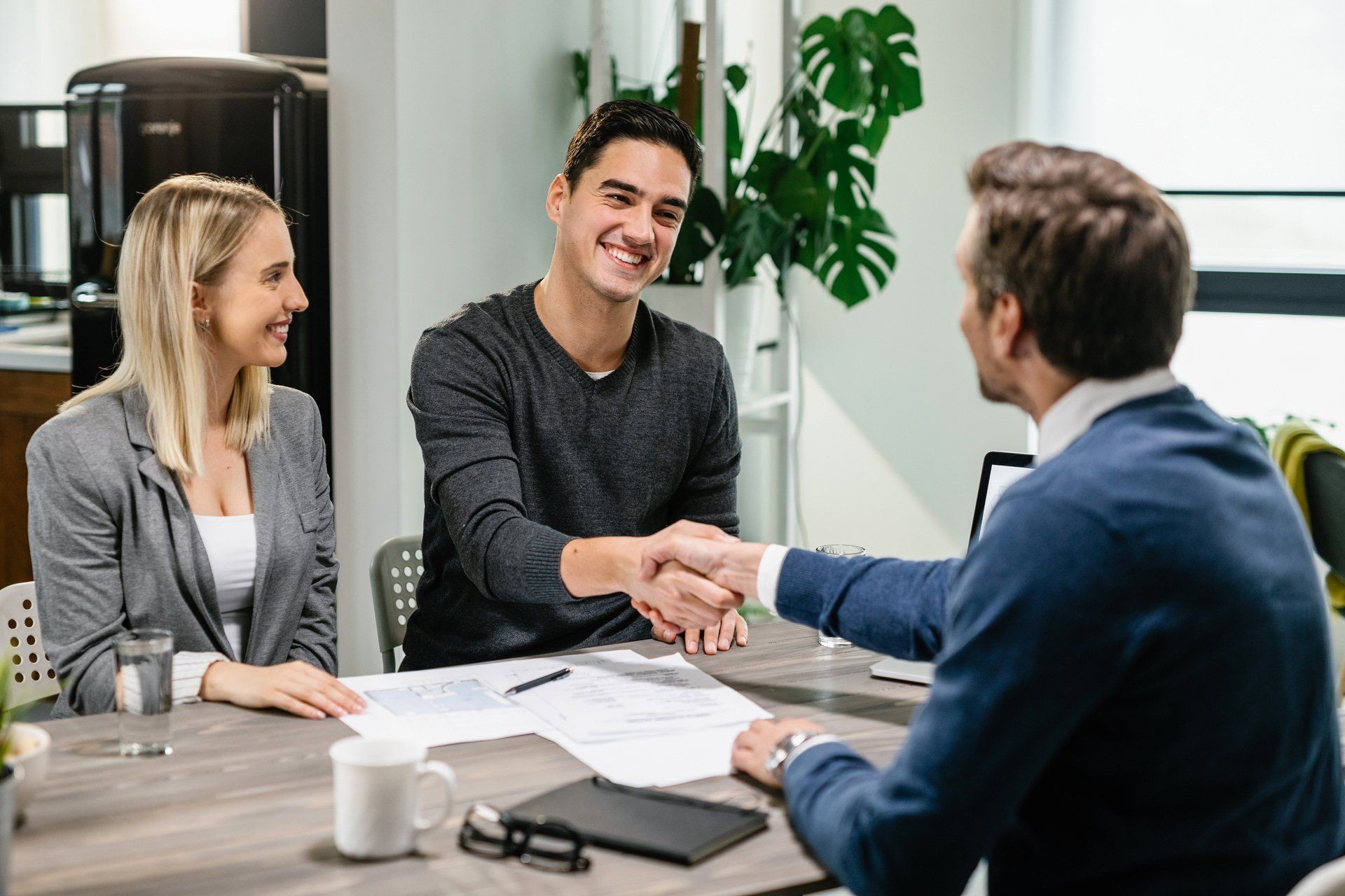 Young Happy Couple Shaking Hands With Their Financial Advisor — Bradenton, FL — Peninsula Asset Management