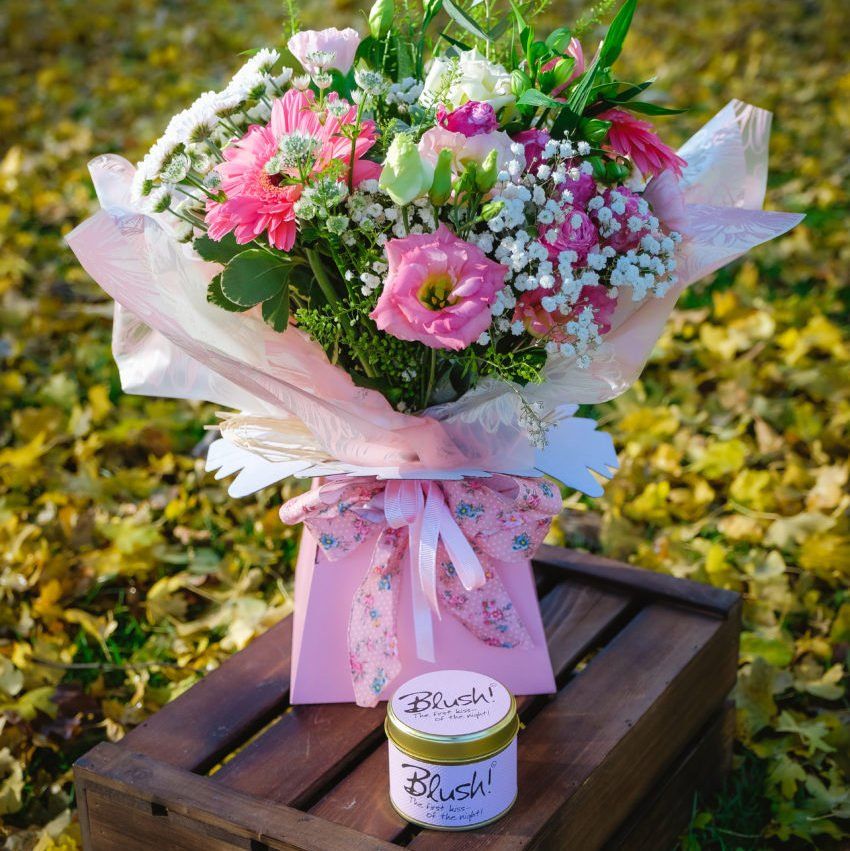 Bouquet of pink and white flowers in a pink gift box with a jar of