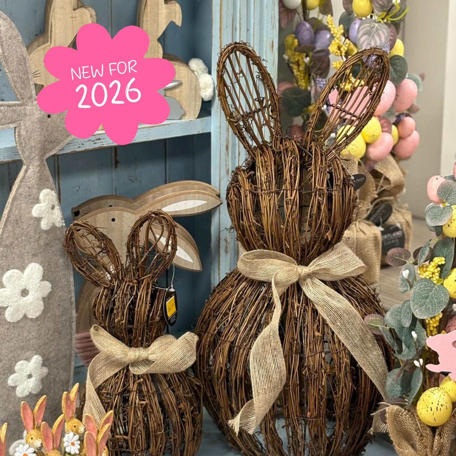 Easter bunny decor, two woven brown rabbits with ribbon bows, in front of a shelf.