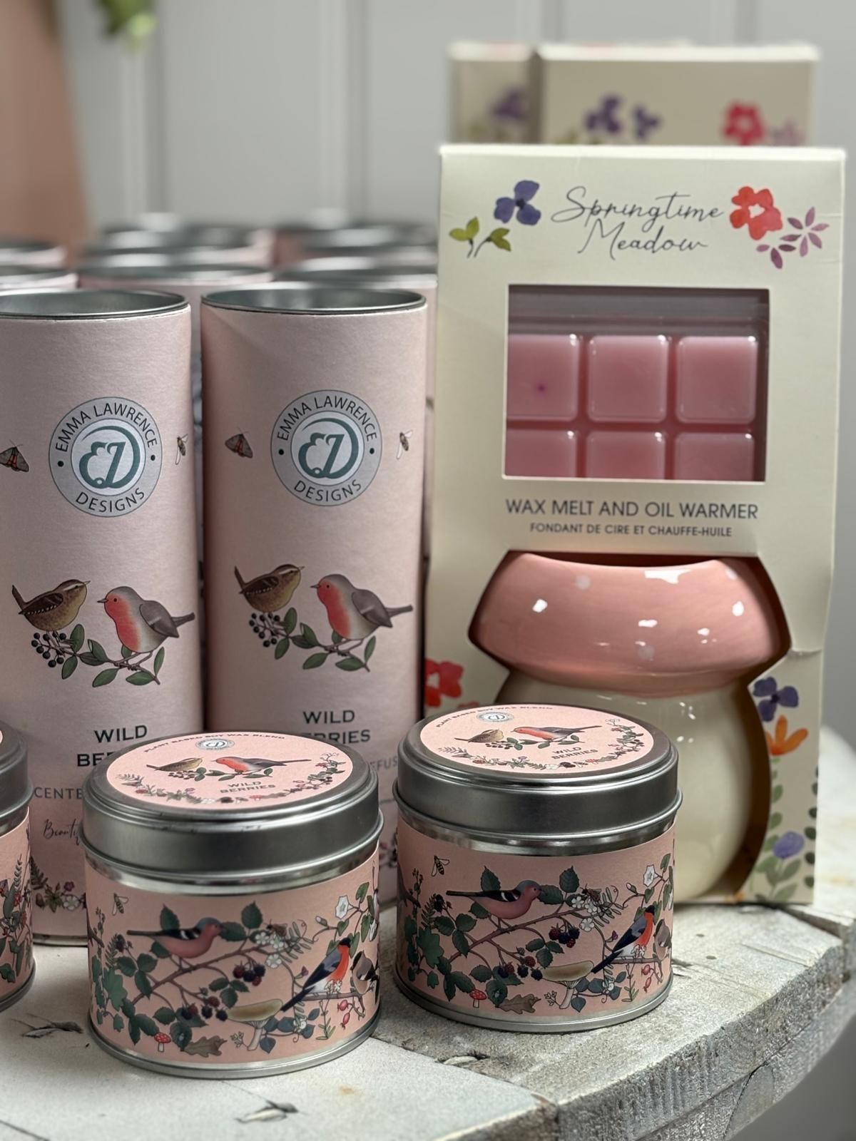 Pink scented candles and wax melt warmer with floral and bird designs.