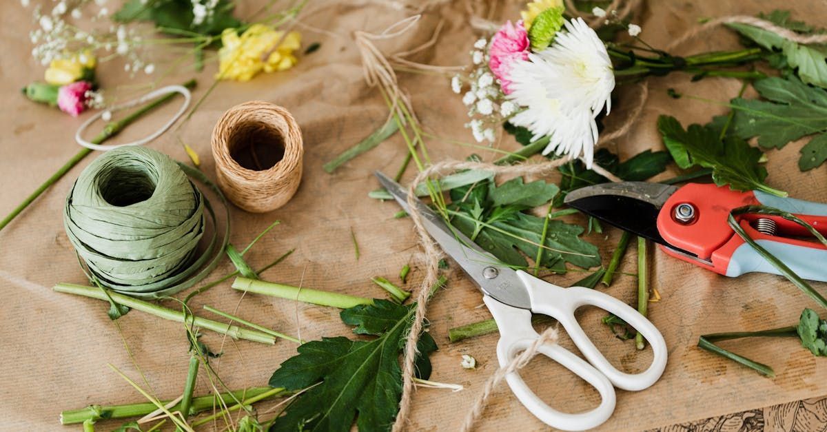 Floral arrangement materials on brown paper: flowers, twine, scissors, clippers, greenery.