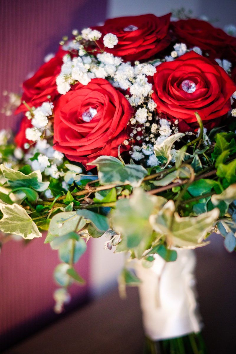 Red rose bouquet with baby's breath and ivy, jewel-centered roses, wrapped stem.