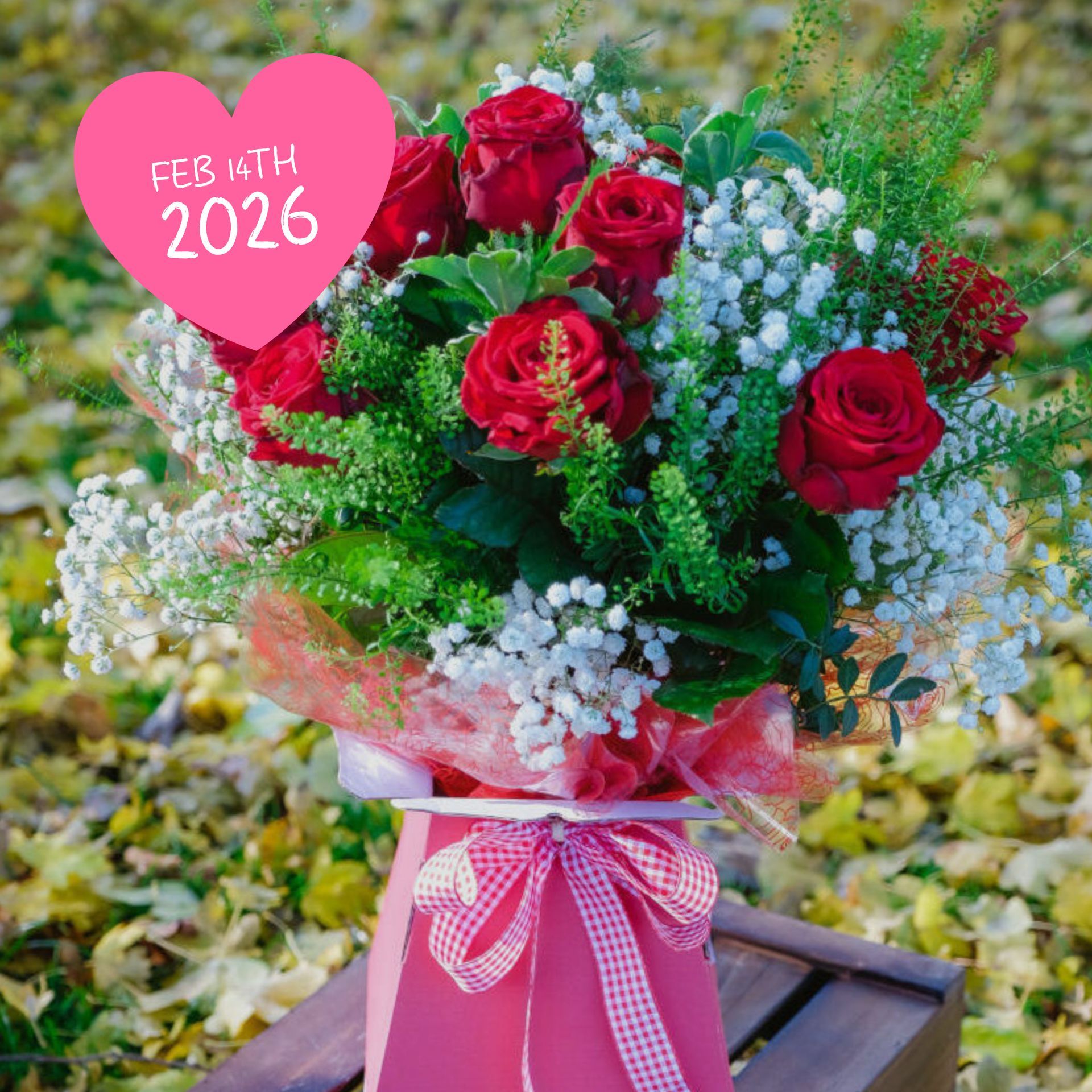 Bouquet of red roses with baby's breath, greenery, and pink container with "Feb 4th 2026" heart.