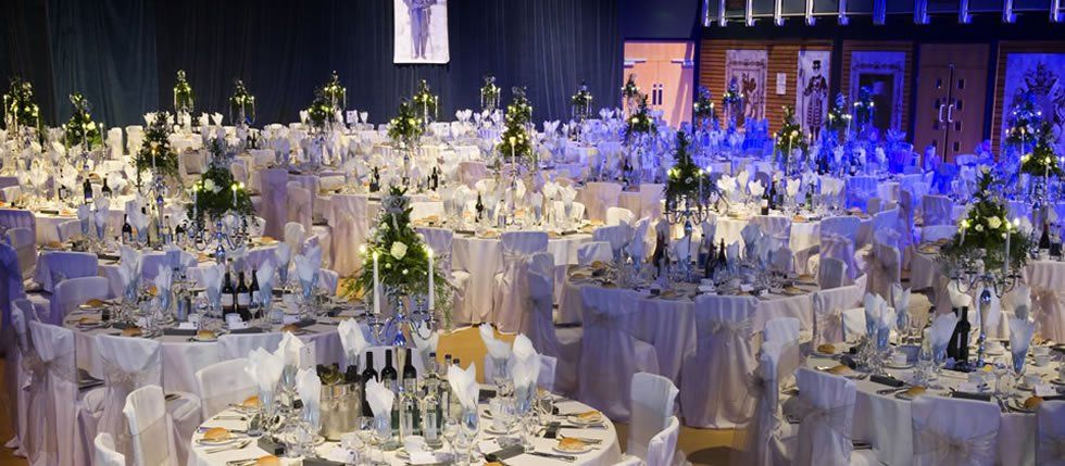 Elegant banquet hall with round tables, white linens, and floral centerpieces.