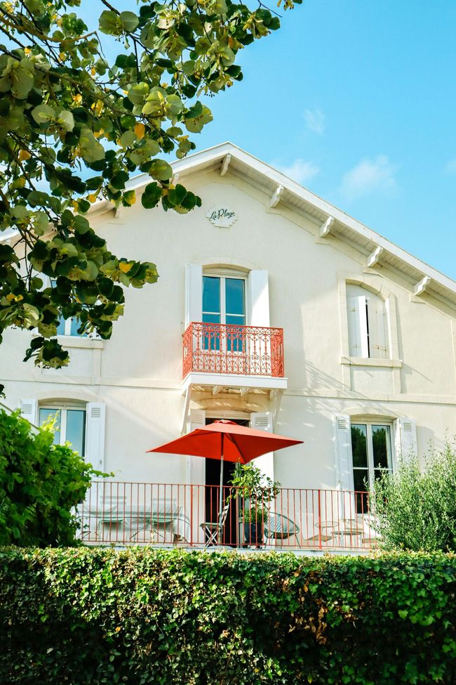 Une maison blanche avec un parapluie rouge devant.