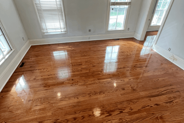 A living room with hardwood floors and two windows.