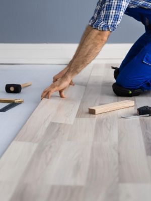 A man is installing a wooden floor in a room.