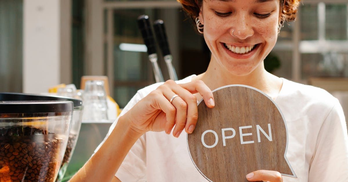 A woman is holding a wooden sign that says open.