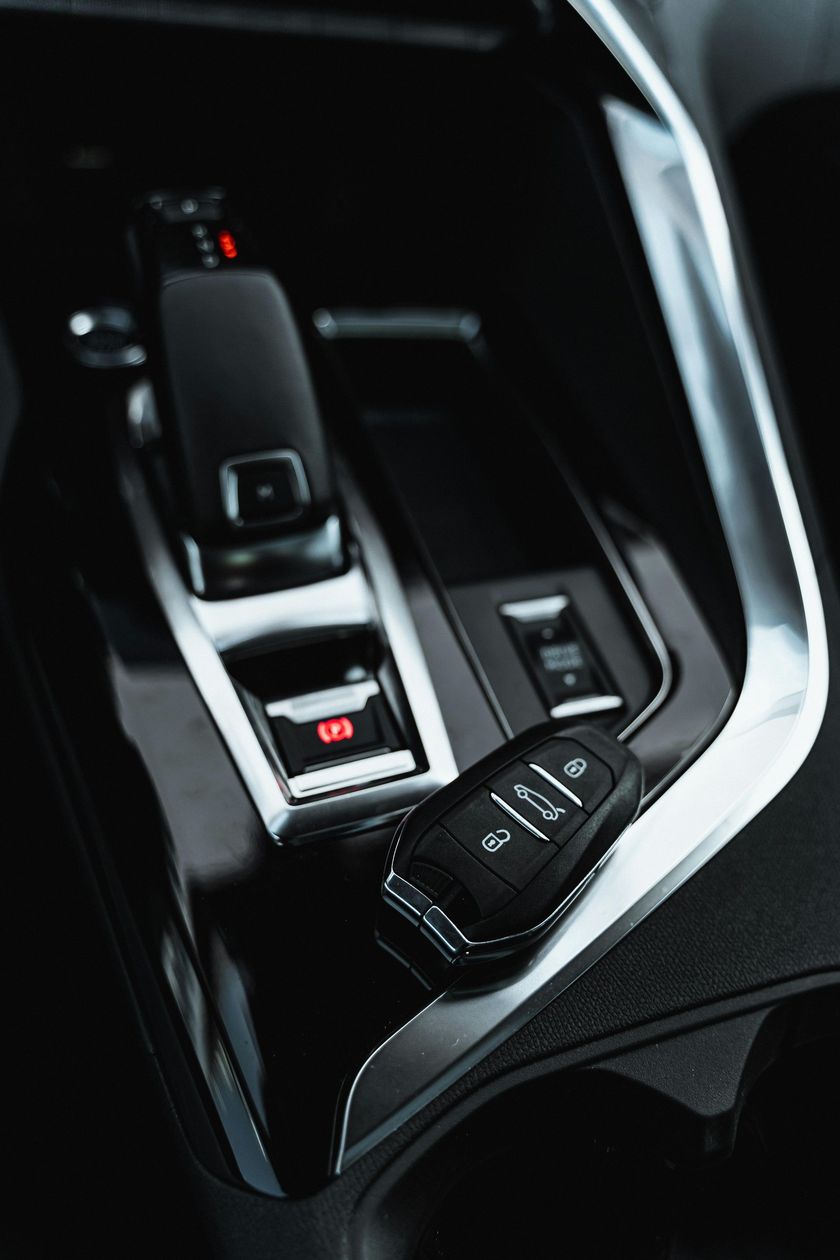 Car key on a glossy black console with gear shift. Silver trim, close-up.