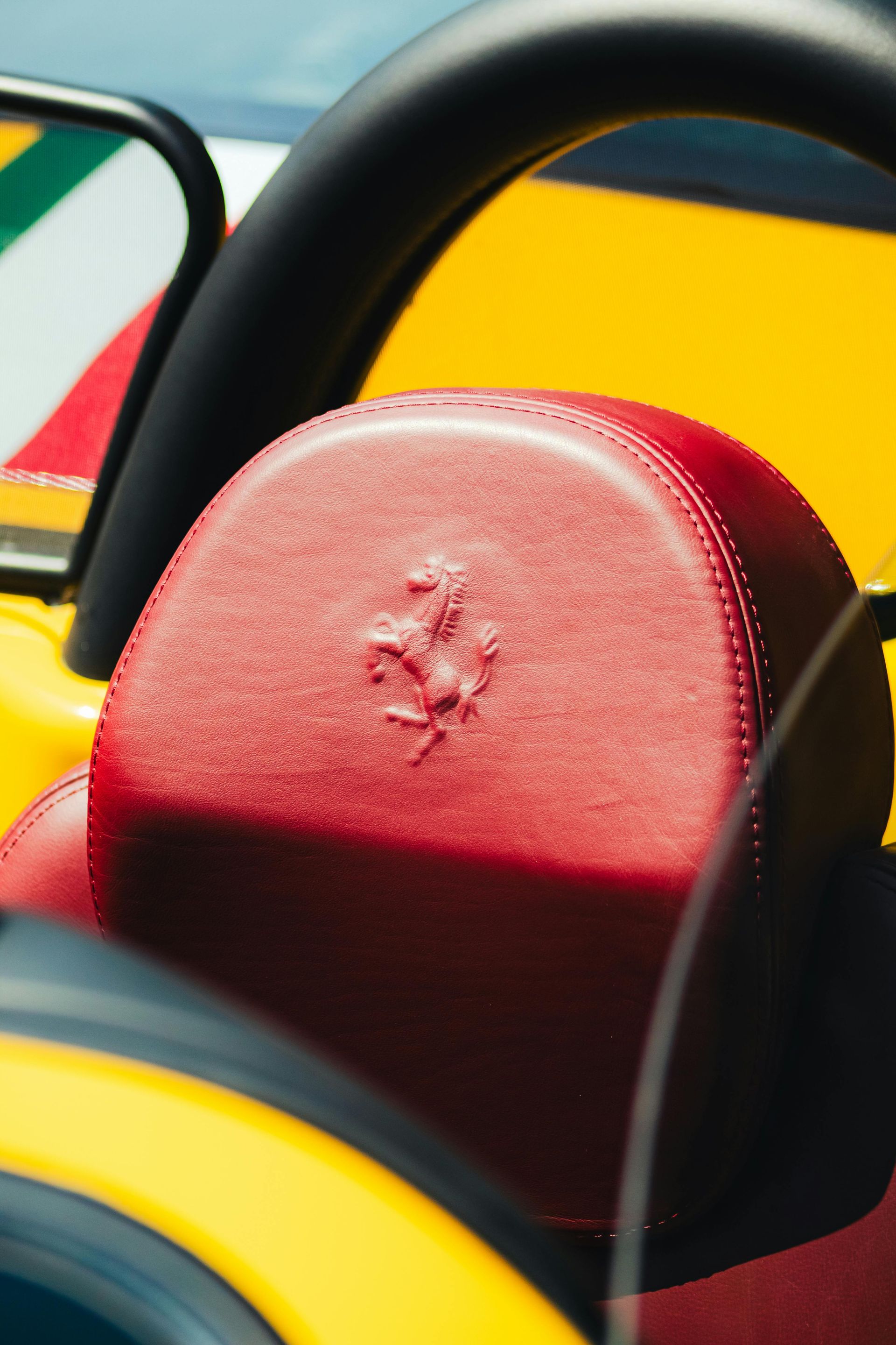Red leather car seat with Ferrari logo, yellow car exterior.
