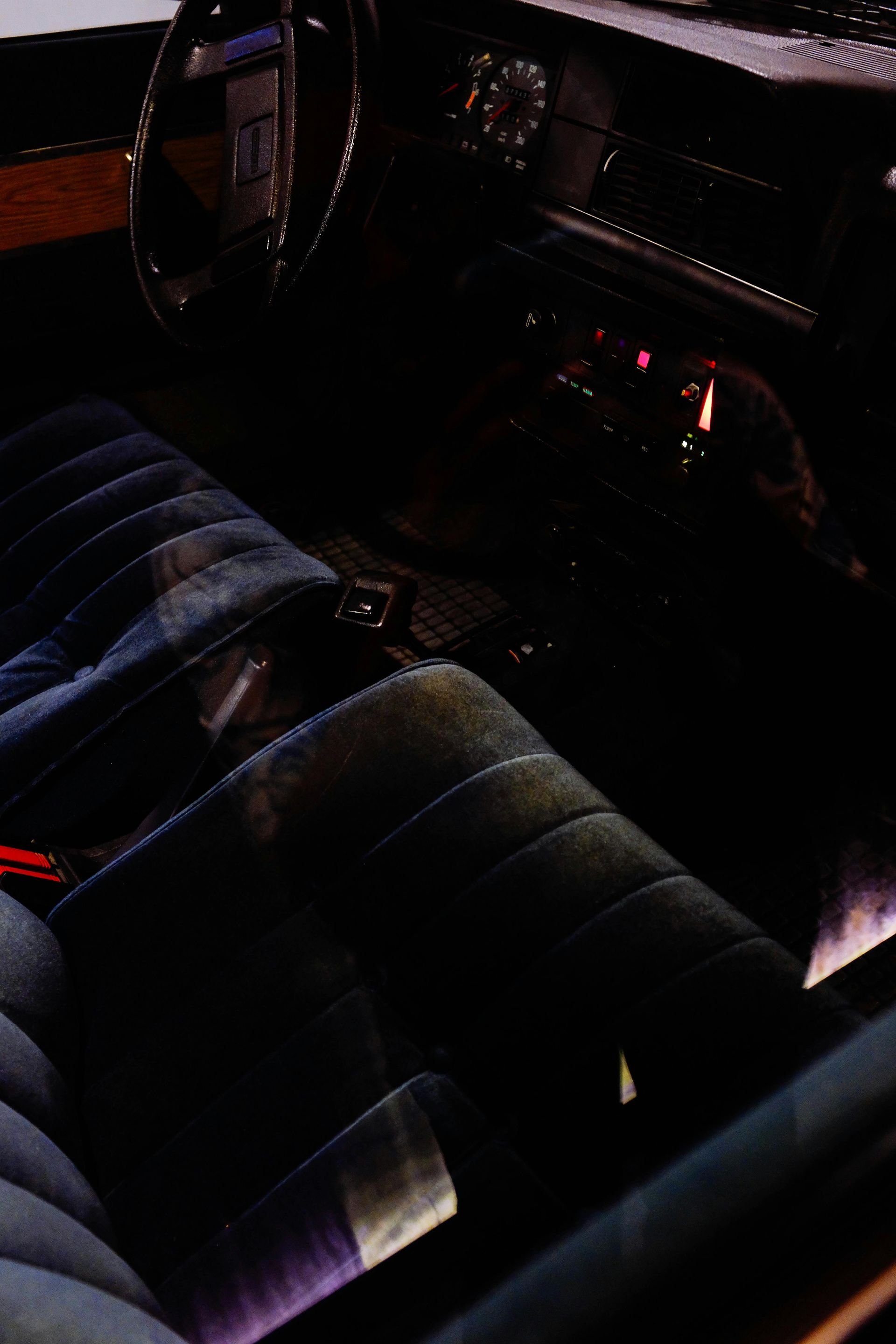 Dark car interior with blue upholstered seats and steering wheel.