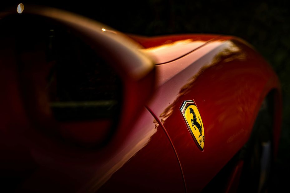 Red Ferrari car with yellow logo, side view.