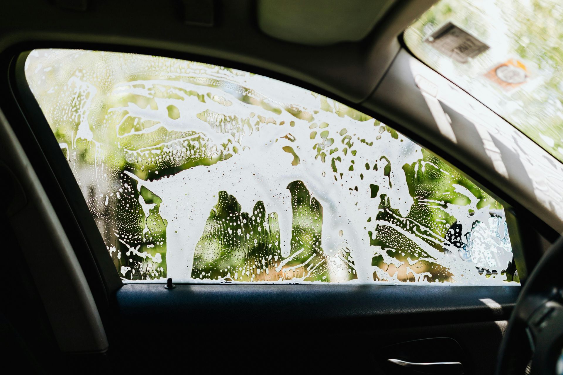 Soapy car window; a person is washing the exterior of the car.