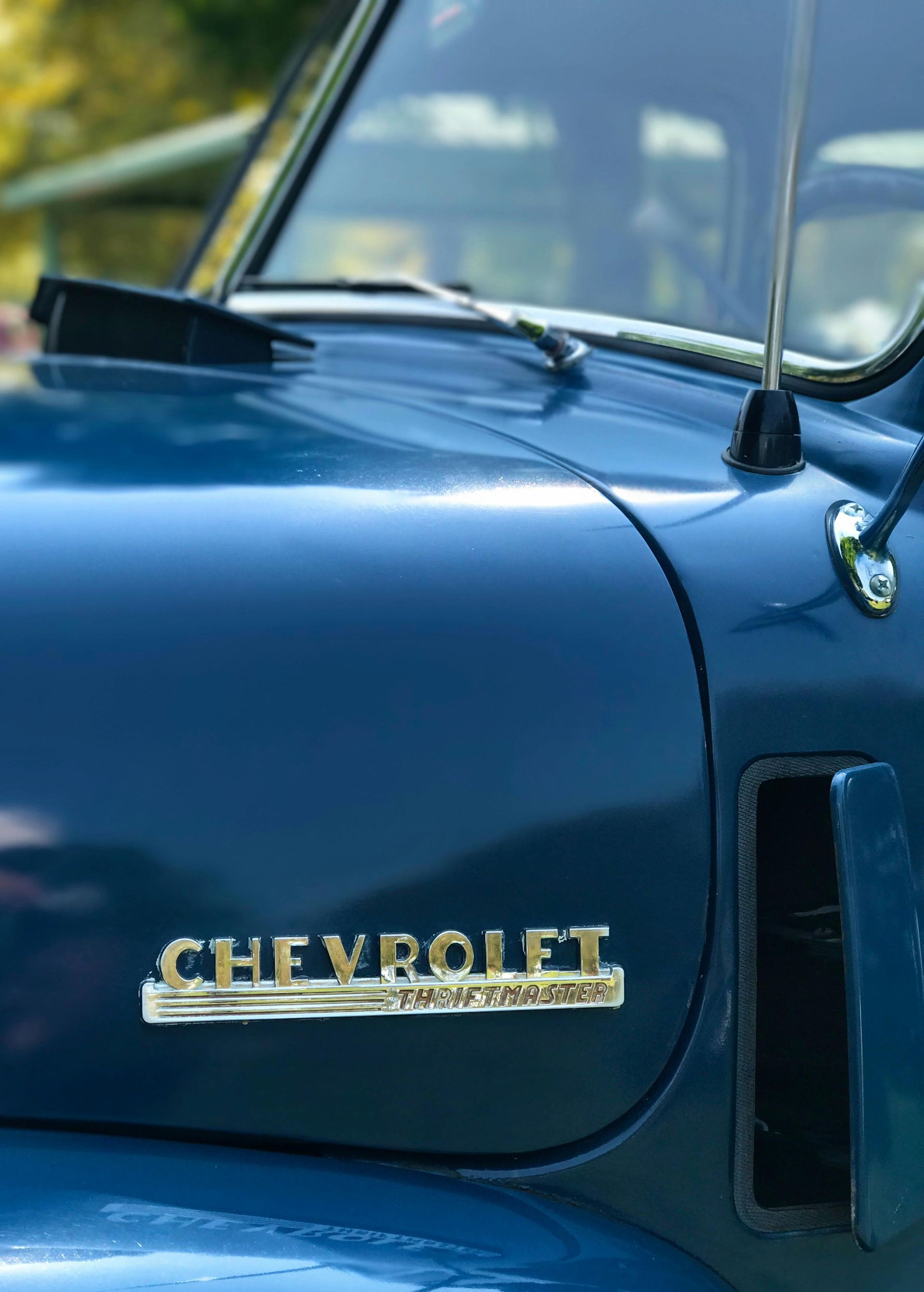 Blue Chevrolet truck hood with gold lettering, close-up.