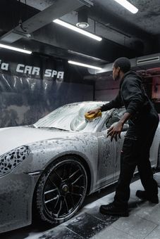 Man washing a white car with foam at a car wash.