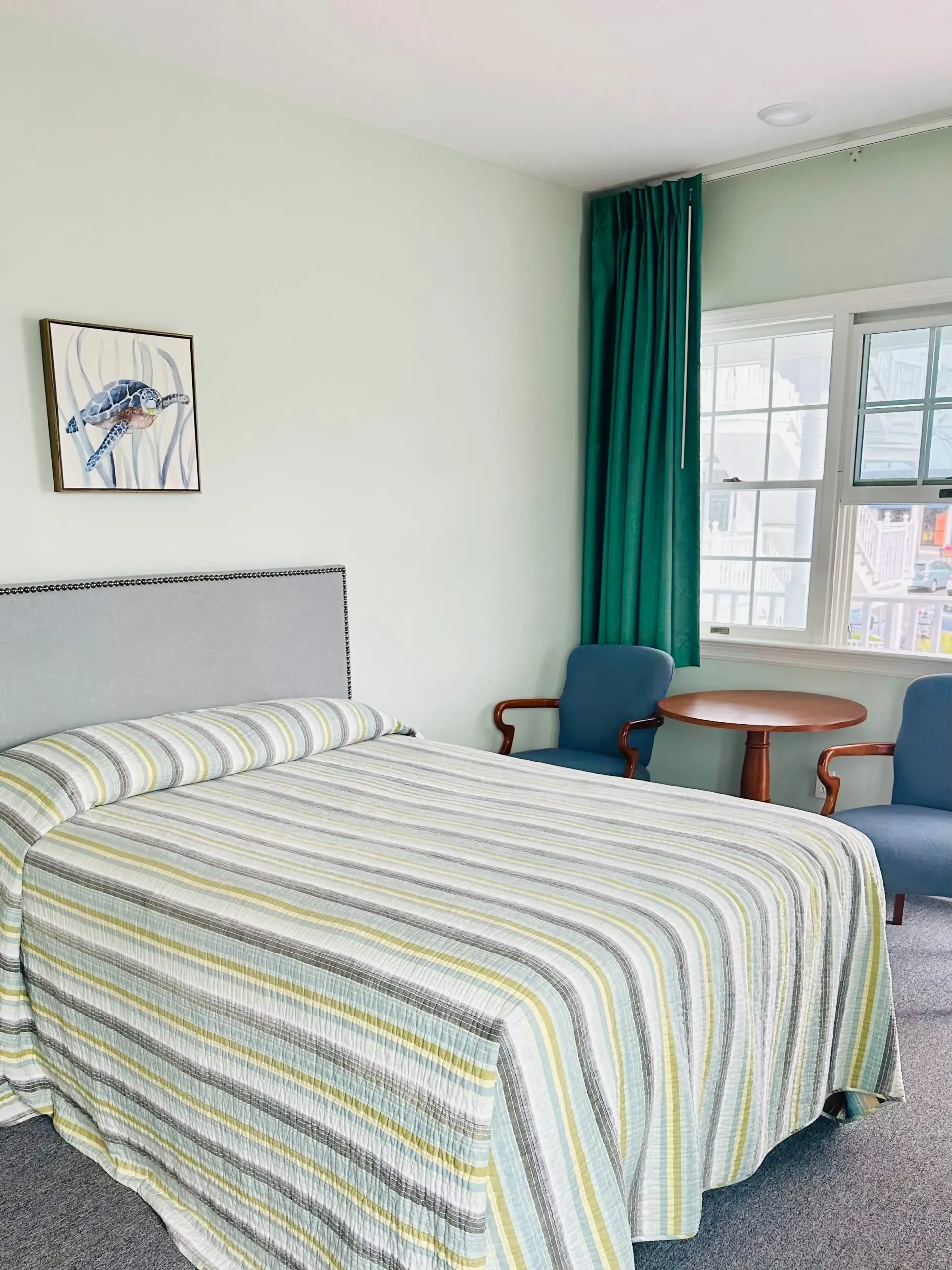 A hotel room with a bed , chairs , table and window.