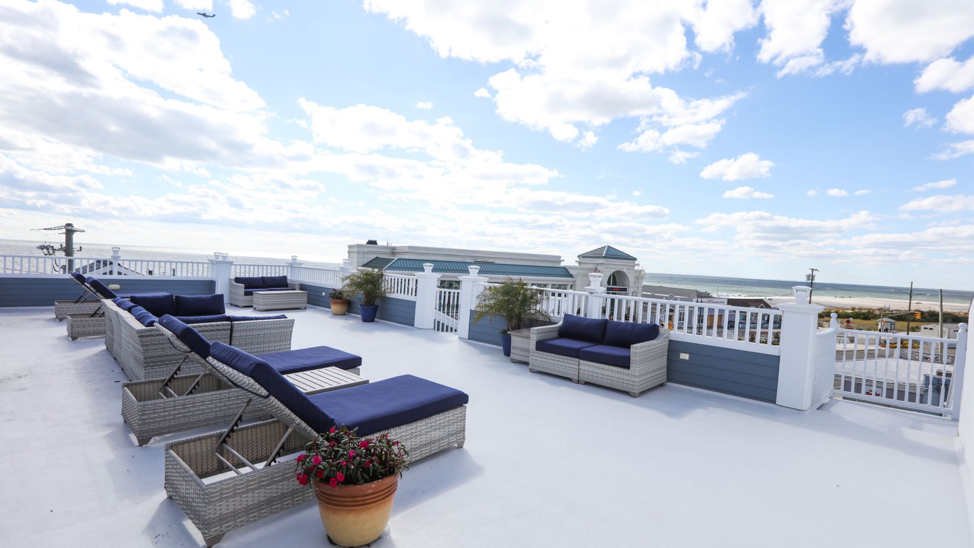 A rooftop deck with wicker furniture and a view of the ocean.
