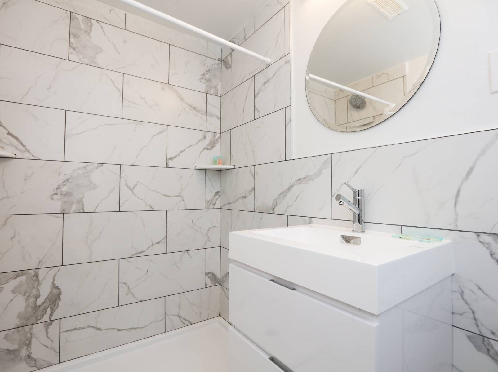 A bathroom with marble tiles and a sink and mirror