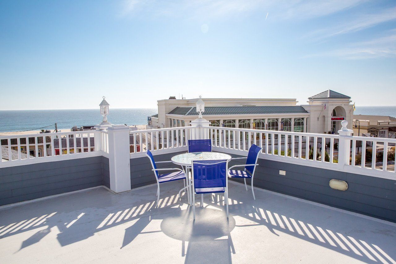 A balcony with a table and chairs overlooking the ocean.