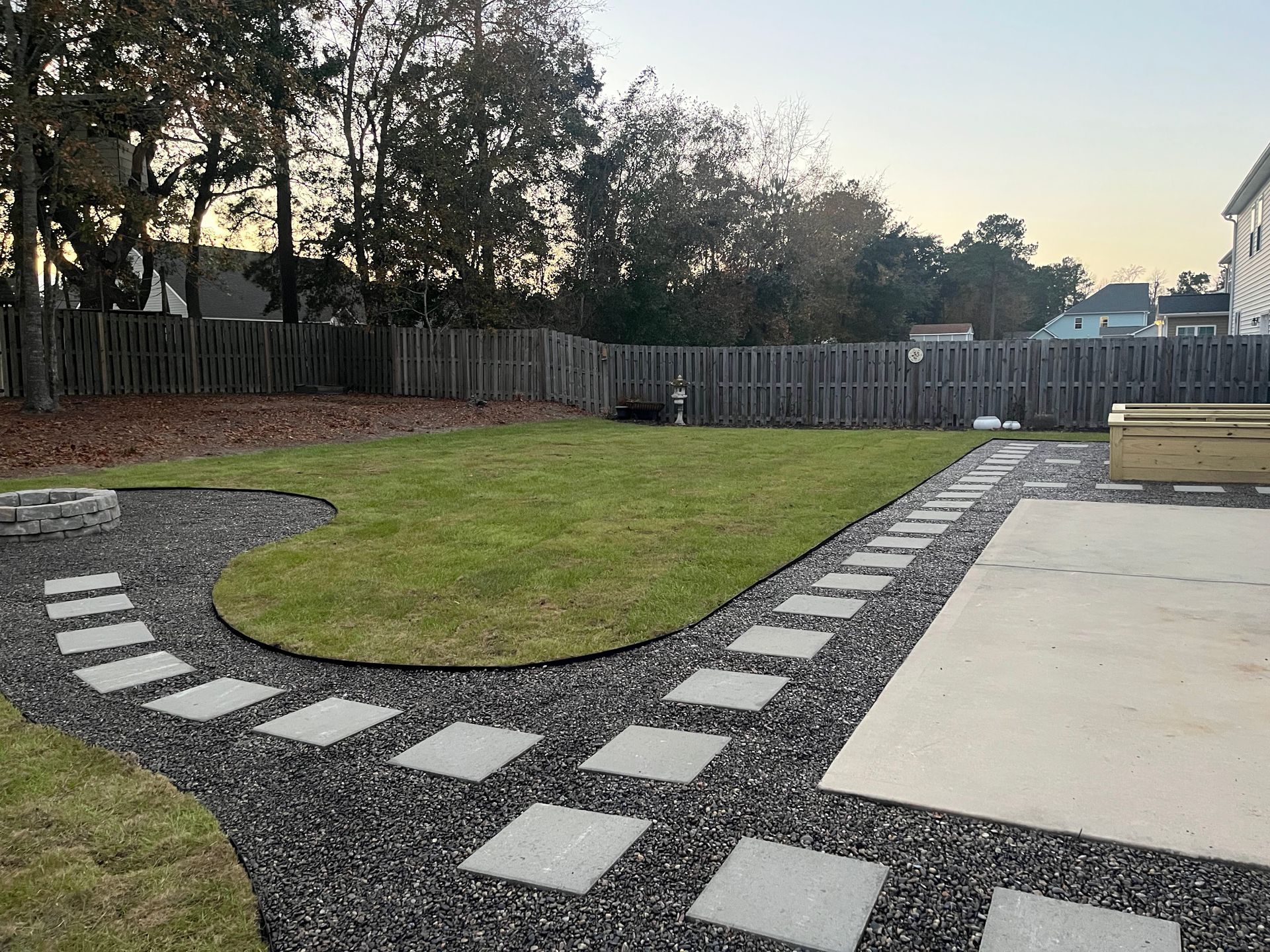 A backyard with a fence and a walkway leading to it.