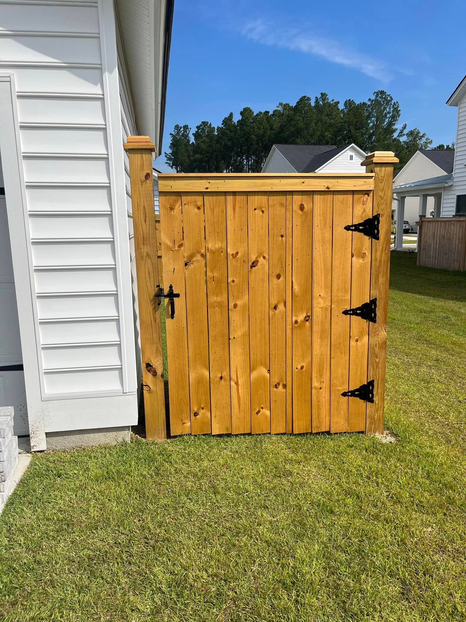 A wooden gate is sitting in the grass next to a white house.