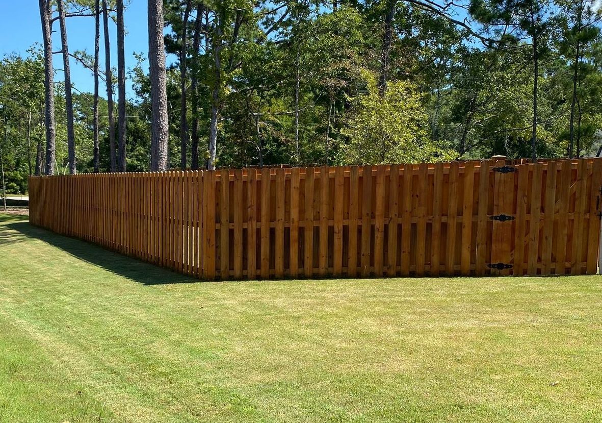 A wooden fence is sitting in the middle of a lush green field.