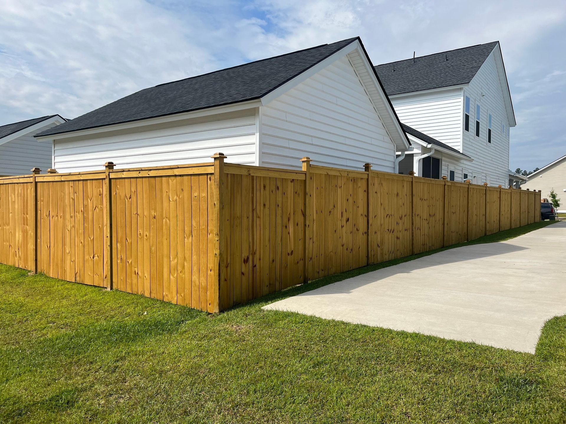 A wooden fence is in front of a white house.