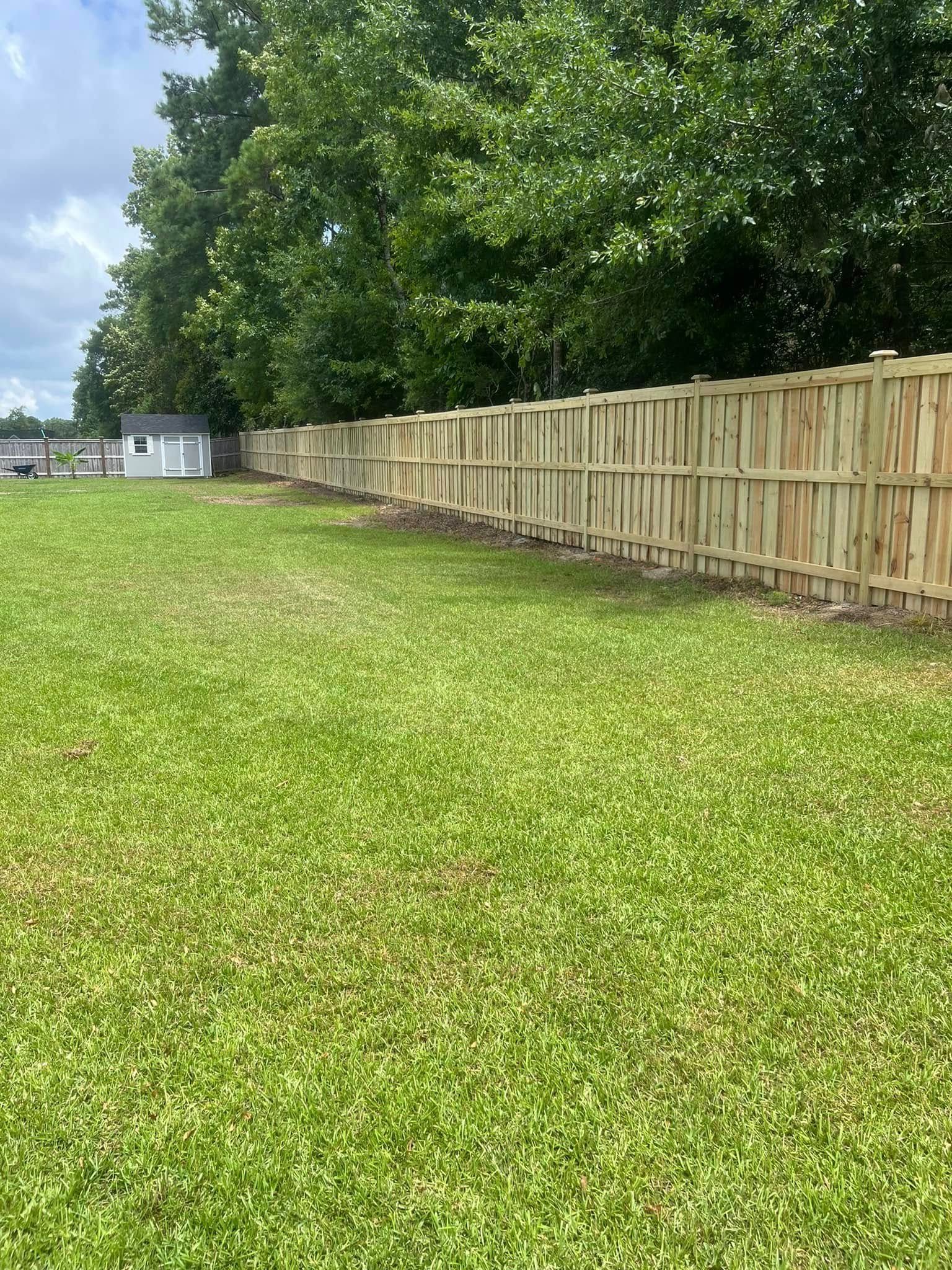 A wooden fence surrounds a lush green field.