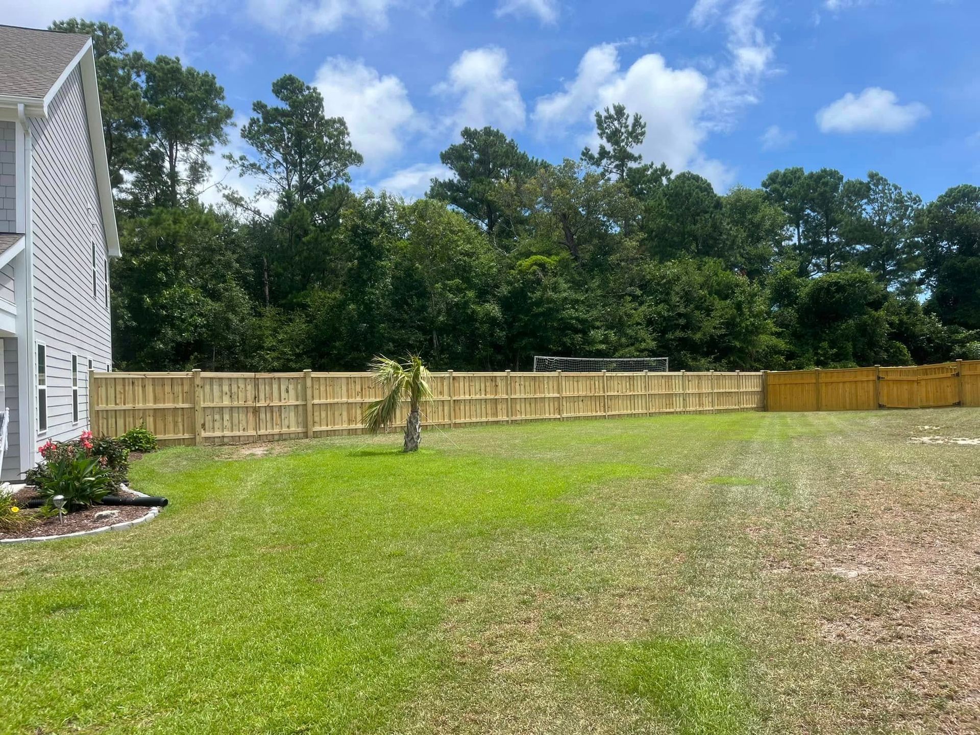 There is a wooden fence in the backyard of a house.