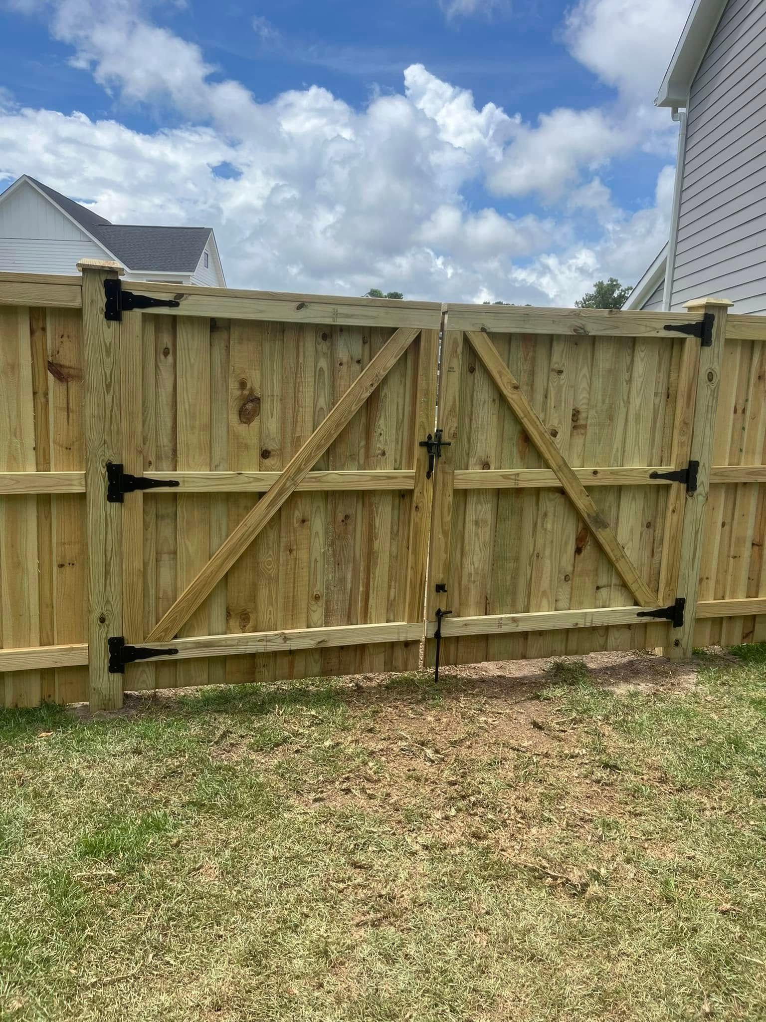 A wooden fence with a gate in the backyard of a house.