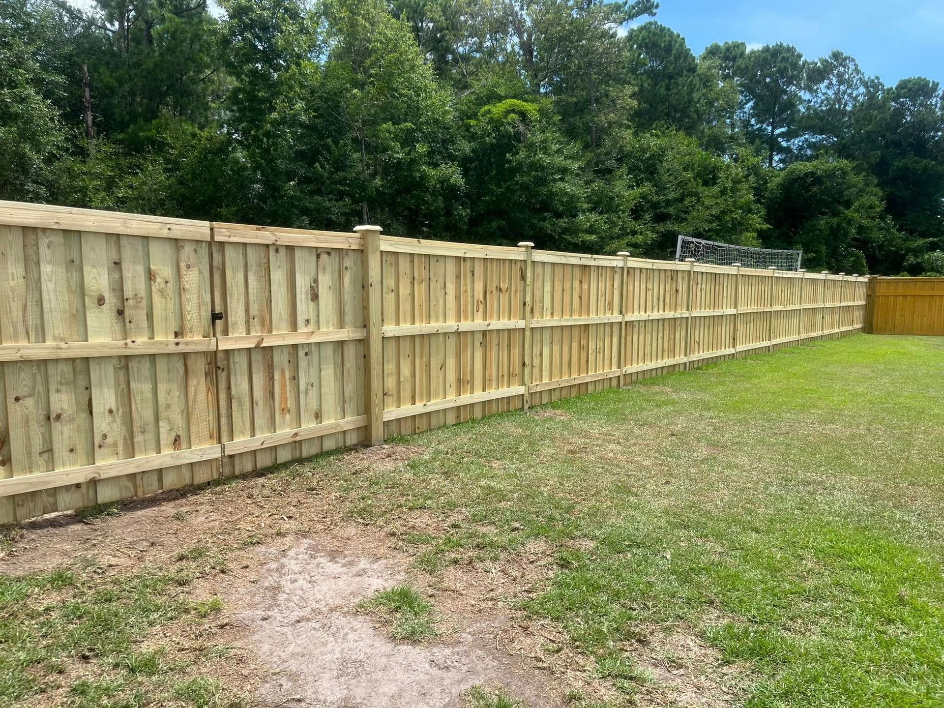 A wooden fence is sitting in the middle of a lush green field.