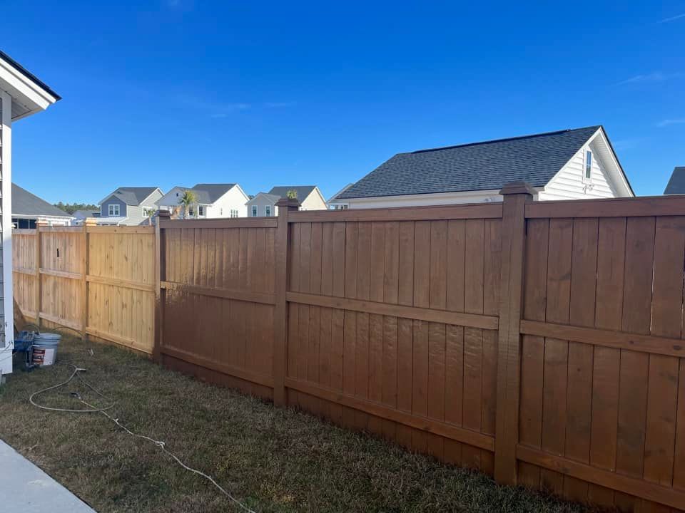 A wooden fence is in the backyard of a house.