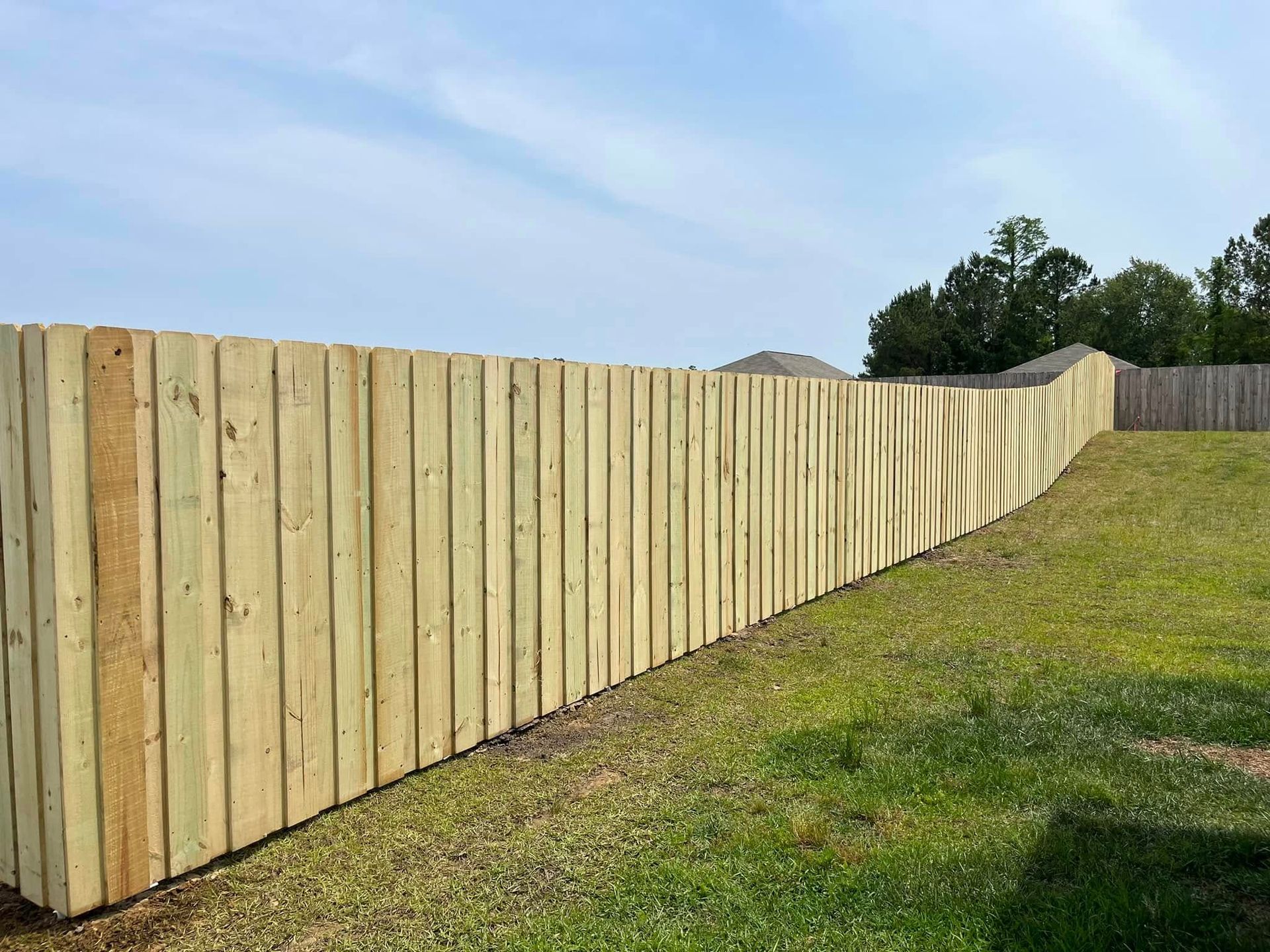 A long wooden fence is sitting on top of a lush green field.