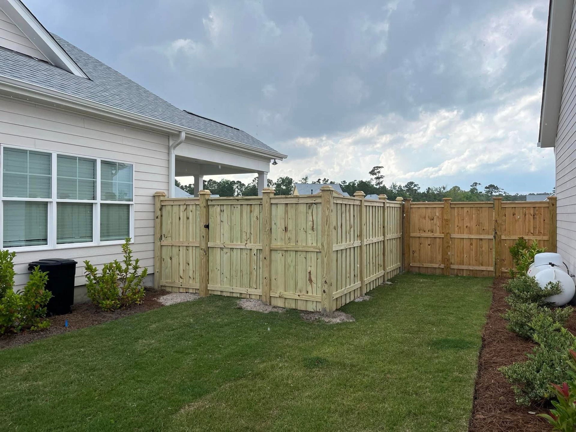 A wooden fence is in the backyard of a house.