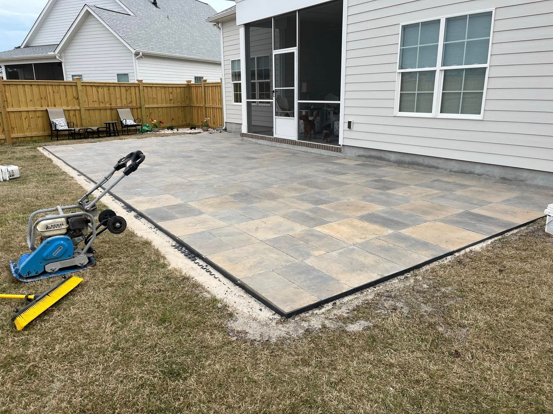 A patio is being built in the backyard of a house.