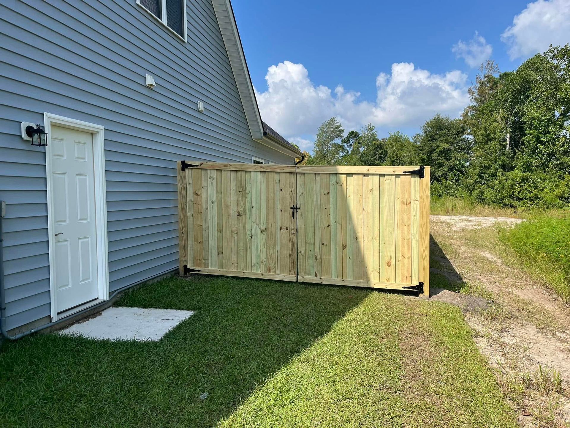 A wooden fence is in the backyard of a house.