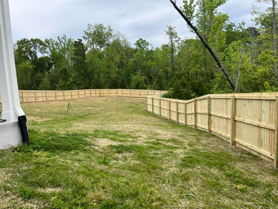 A wooden fence surrounds a large grassy field.