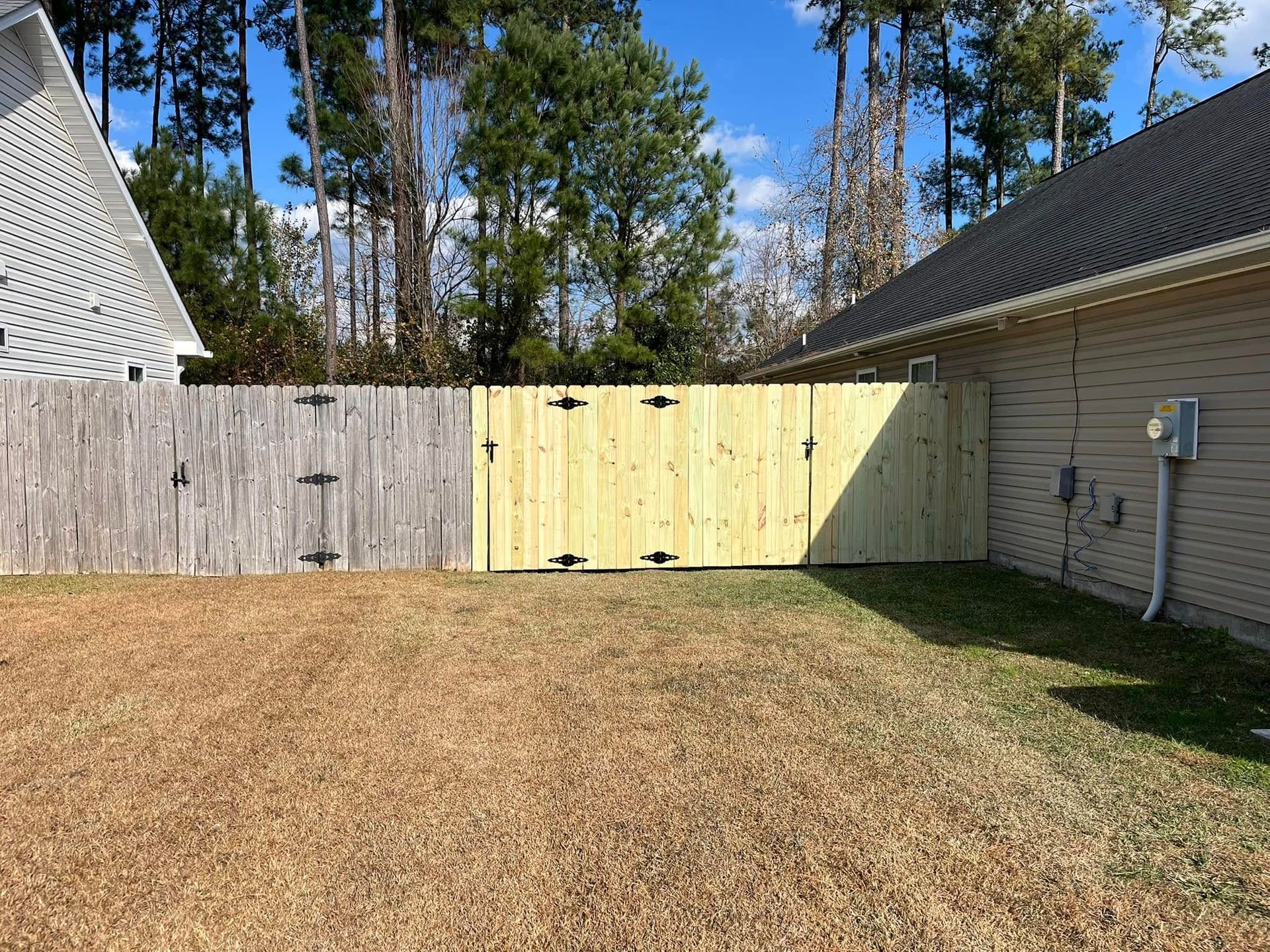 There is a wooden fence in the backyard of a house.